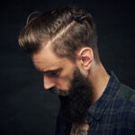 Close up portrait of bearded male with long hair over dark background.