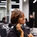 A professional girl hairdresser makes a client haircut. The girl is sitting in a mask in beauty the salon