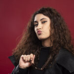 Woman in all black outfit holding glasses and posing. High quality photo